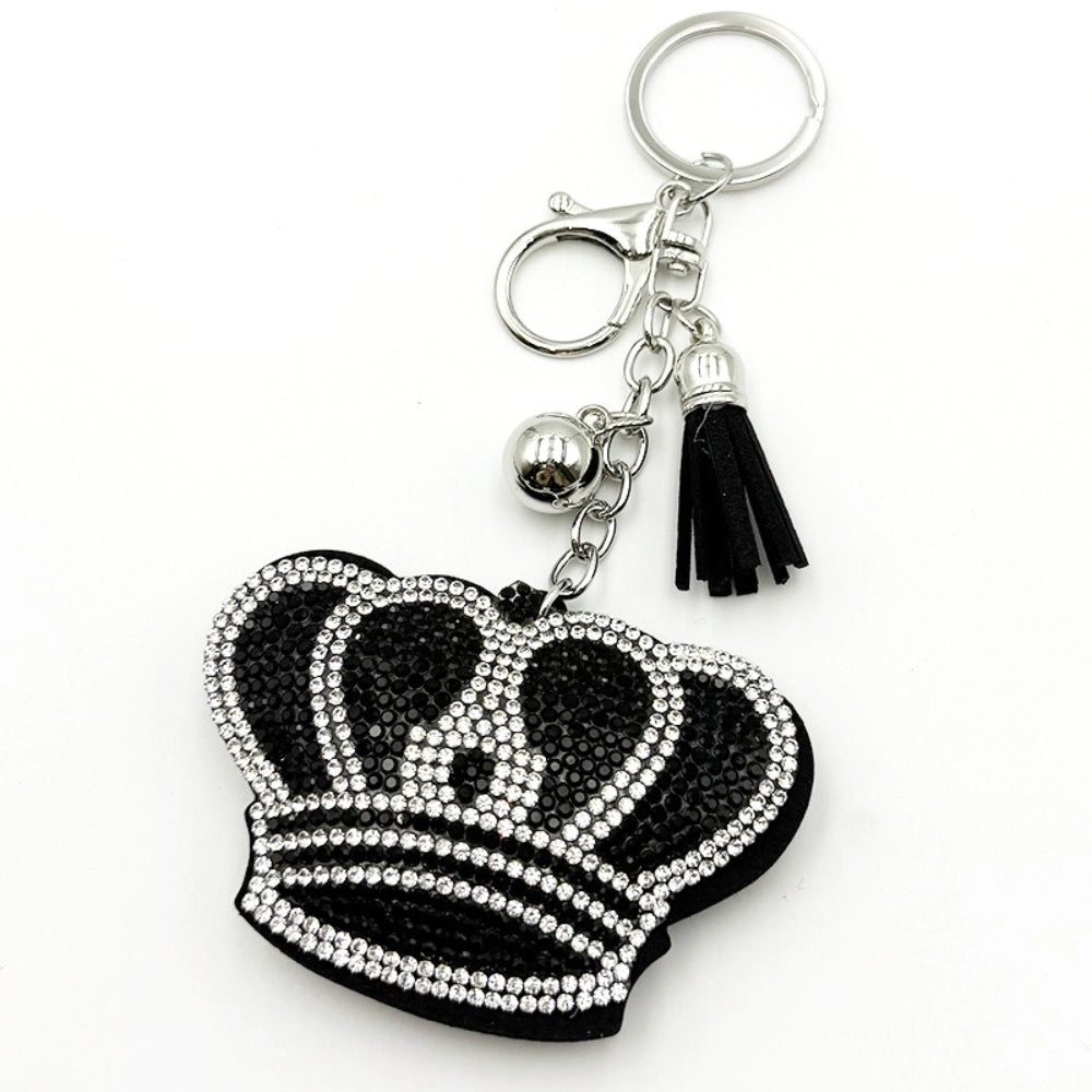 Black and clear rhinestone crown shaped keychain charm with silver lobster clasp, chain, silver bead, and black leather tassel on white background.