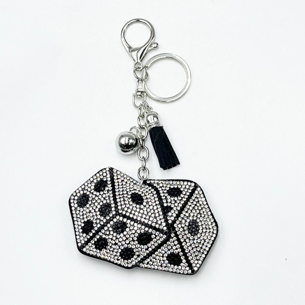 Black and white crystal rhinestone dice keychain charm with silver lobster clasp, ball bead, and black tassel on white background