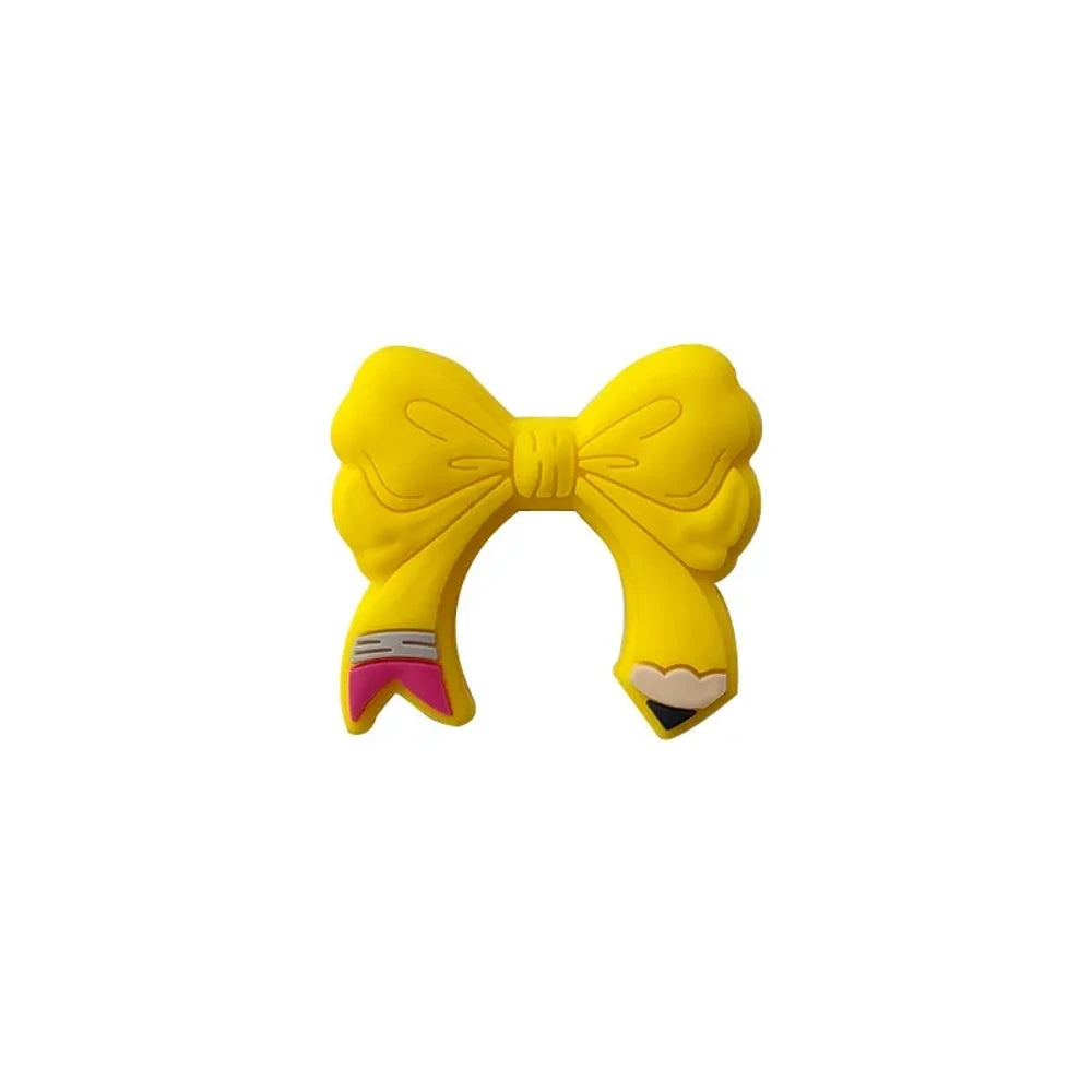 Assorted colorful bow tie silicone focal beads in light pink, hot pink, teal, yellow, and magenta displayed on a miniature white bench with pink background - Yellow