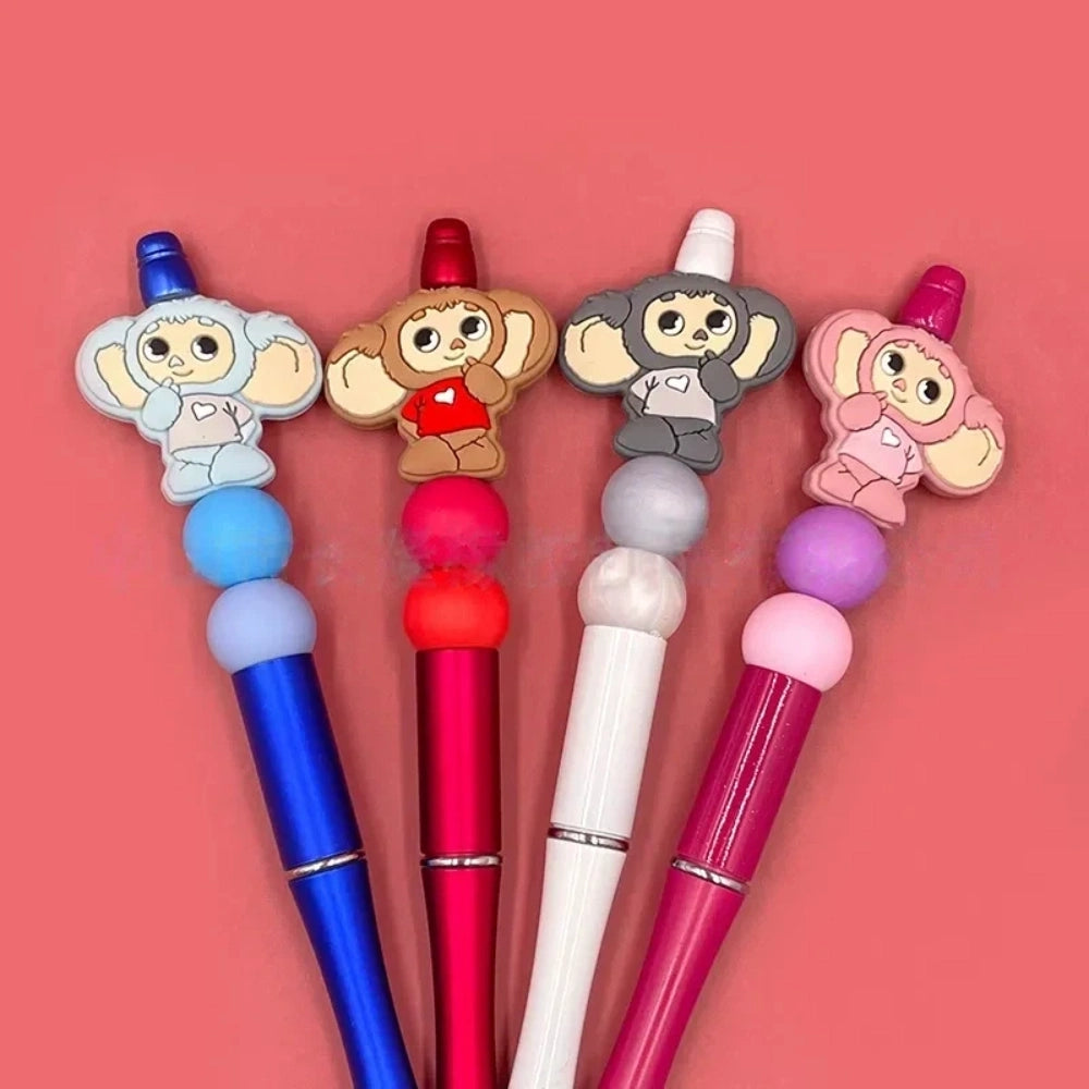 Four Cheburashka silicone focal beads in blue, red, gray, and pink colorways displayed on beadable pens against a pink background.