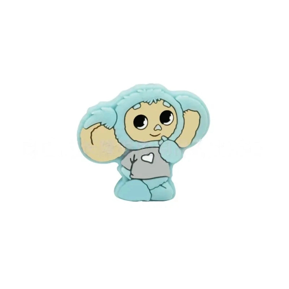 Four Cheburashka silicone focal beads in blue, red, gray, and pink colorways displayed on beadable pens against a pink background. - Blue