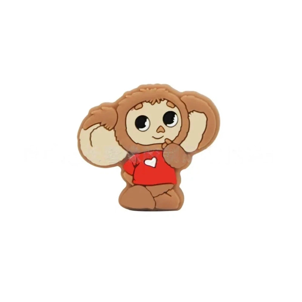 Four Cheburashka silicone focal beads in blue, red, gray, and pink colorways displayed on beadable pens against a pink background. - Camel