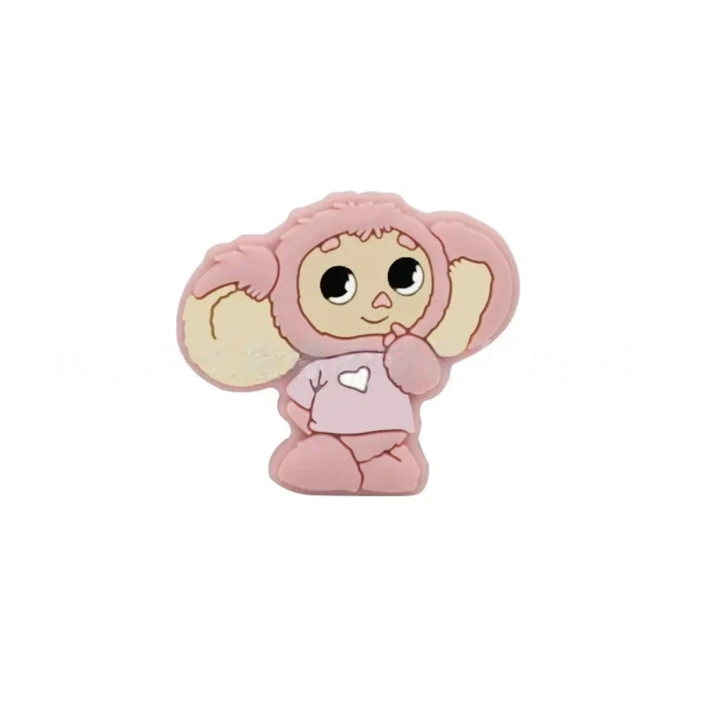 Four Cheburashka silicone focal beads in blue, red, gray, and pink colorways displayed on beadable pens against a pink background. - Pink