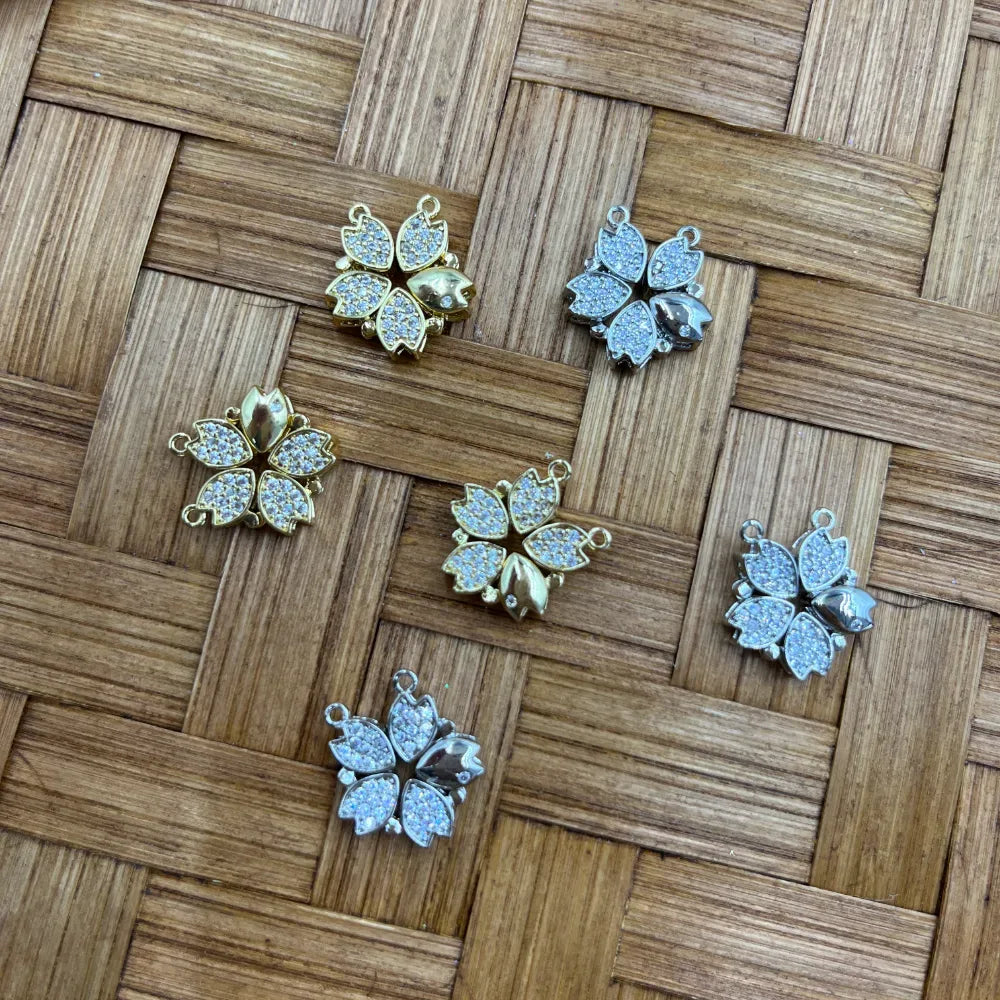 Cherry blossom flower shaped bail beads with pave cubic zirconia crystals in gold and silver finishes displayed on woven bamboo background for DIY jewelry making