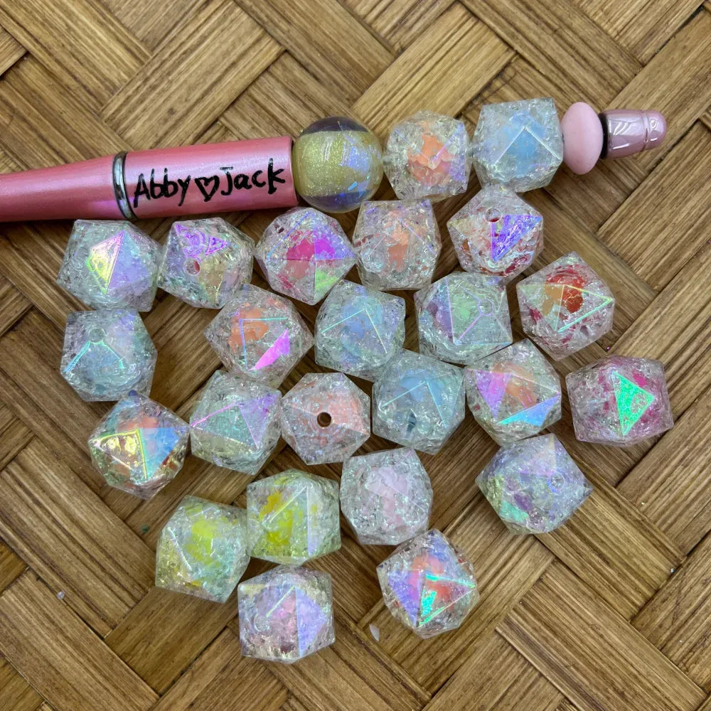 Chunky clear iridescent crackle faceted acrylic beads with pastel AB shimmer beside a pink beadable pen
