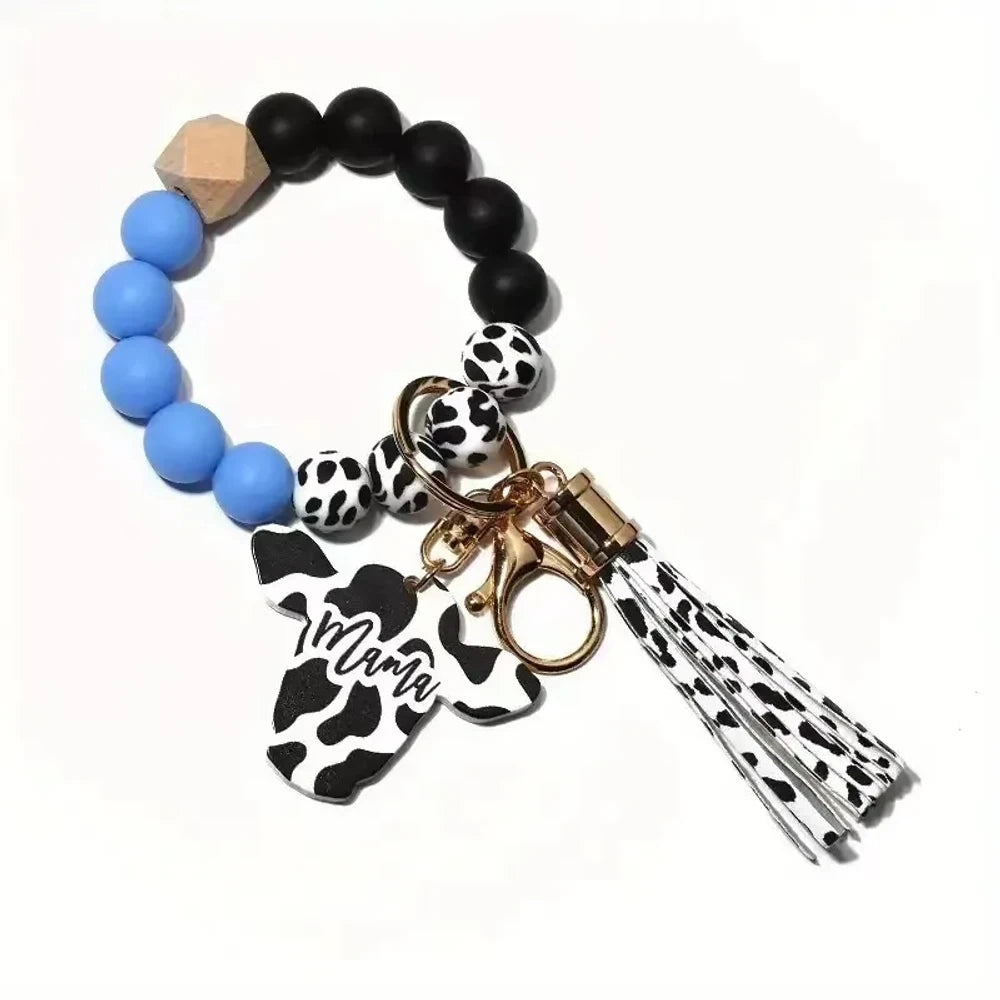 Cow print black and white silicone beads mixed with solid color silicone beads on bracelet keychains with mama butterfly charm and tassel pendants in pink, black, teal, and purple color combinations - Blue