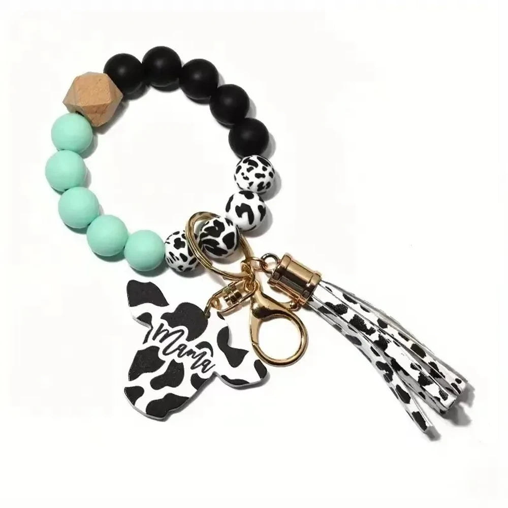 Cow print black and white silicone beads mixed with solid color silicone beads on bracelet keychains with mama butterfly charm and tassel pendants in pink, black, teal, and purple color combinations - Green-2