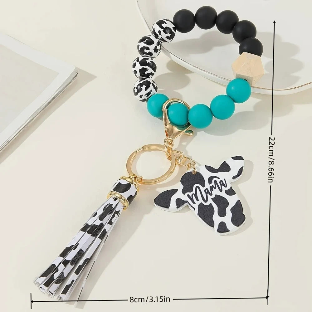 Cow print black and white silicone beads mixed with solid color silicone beads on bracelet keychains with mama butterfly charm and tassel pendants in pink, black, teal, and purple color combinations - Green