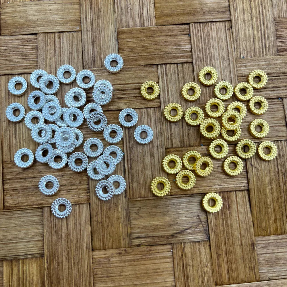 Silver and gold dotted edge rondelle metal spacer beads with center hole displayed on woven bamboo surface, suitable for beadable pens, bracelets, and DIY jewelry making.
