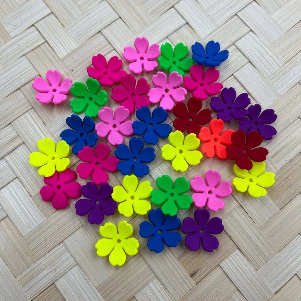 Assorted neon and bright colored flower shaped acrylic spacer beads in pink, blue, yellow, green, purple, red and orange on a woven surface