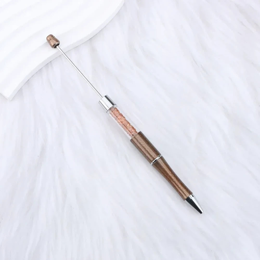 25-piece set of multicolor glitter crystal beadable plastic pens with silver accents and bead bar tops, arranged in a fan display on white fabric - 1
