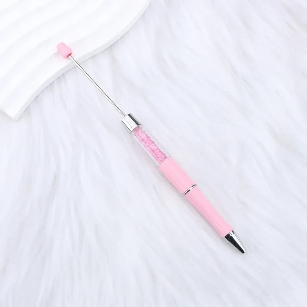 25-piece set of multicolor glitter crystal beadable plastic pens with silver accents and bead bar tops, arranged in a fan display on white fabric - 10