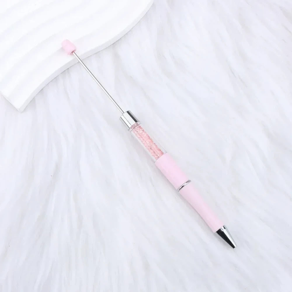 25-piece set of multicolor glitter crystal beadable plastic pens with silver accents and bead bar tops, arranged in a fan display on white fabric - 24
