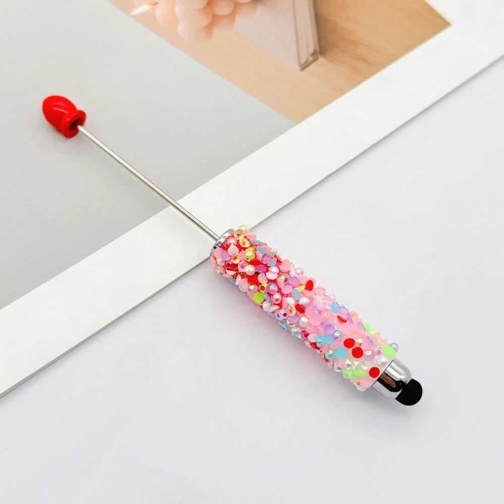 Set of 11 glitter rhinestone beadable pens in assorted colors including white, hot pink, black, multicolor, pink, light pink, teal, brown, purple, blue, and lavender, displayed on a white surface. - 11