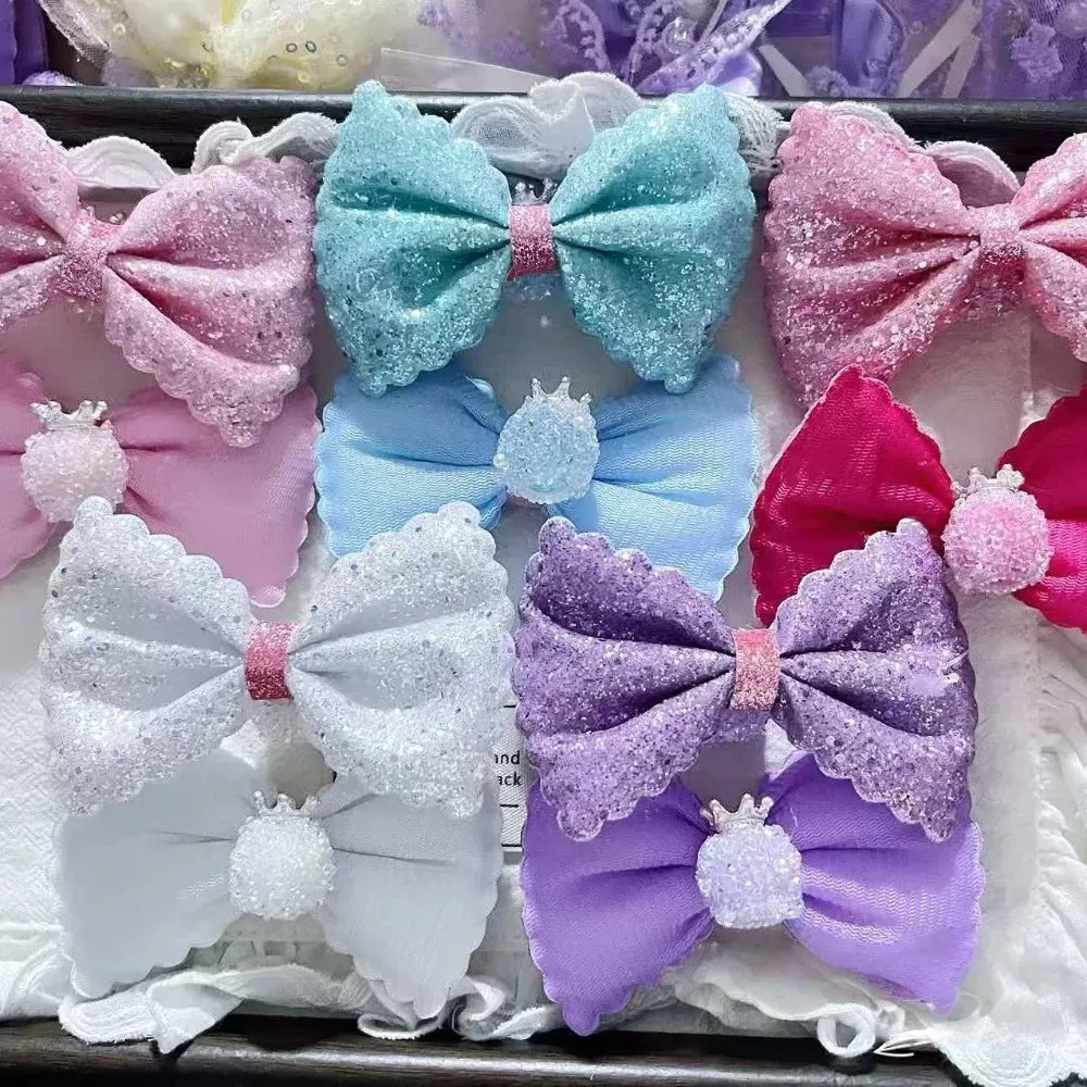 Assorted glitter sequin bow-shaped fancy beads in pink, aqua blue, white, and purple with crown embellishments, displayed in a tray for DIY craft projects.