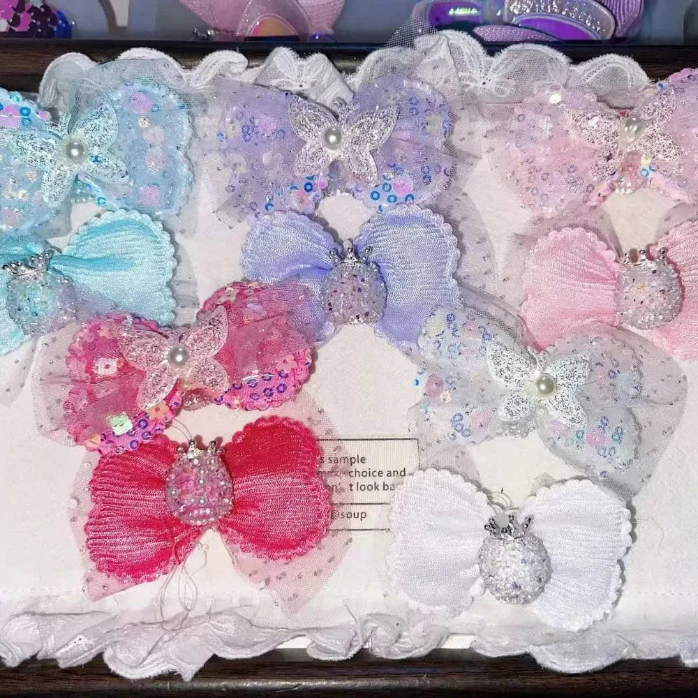 Assorted glitter sequin butterfly bow and flower fabric applique patches in blue, purple, pink, hot pink, red, and white with pearl and rhinestone embellishments on a white display board