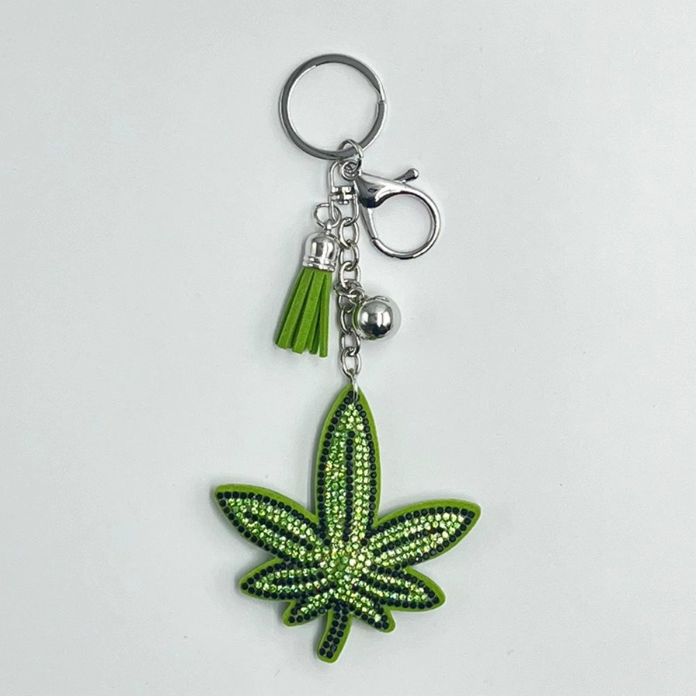 Green rhinestone cannabis leaf keychain charm with green tassel, silver ball, lobster clasp, and key ring on white background.