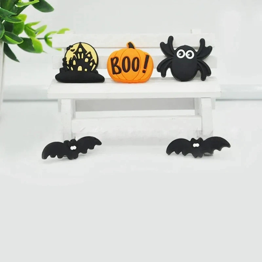 Set of 5 Halloween silicone focal beads including a BOO pumpkin, haunted house, black spider, and two bats displayed on a miniature white bench