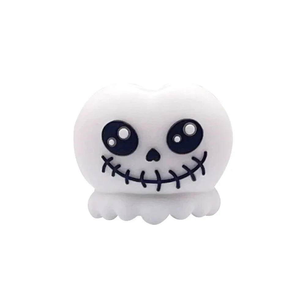 Halloween silicone 3D focal beads featuring skull and Frankenstein monster characters in white, green, and mummy designs, displayed on beadable pens with decorative round beads on a pink background. - Jack