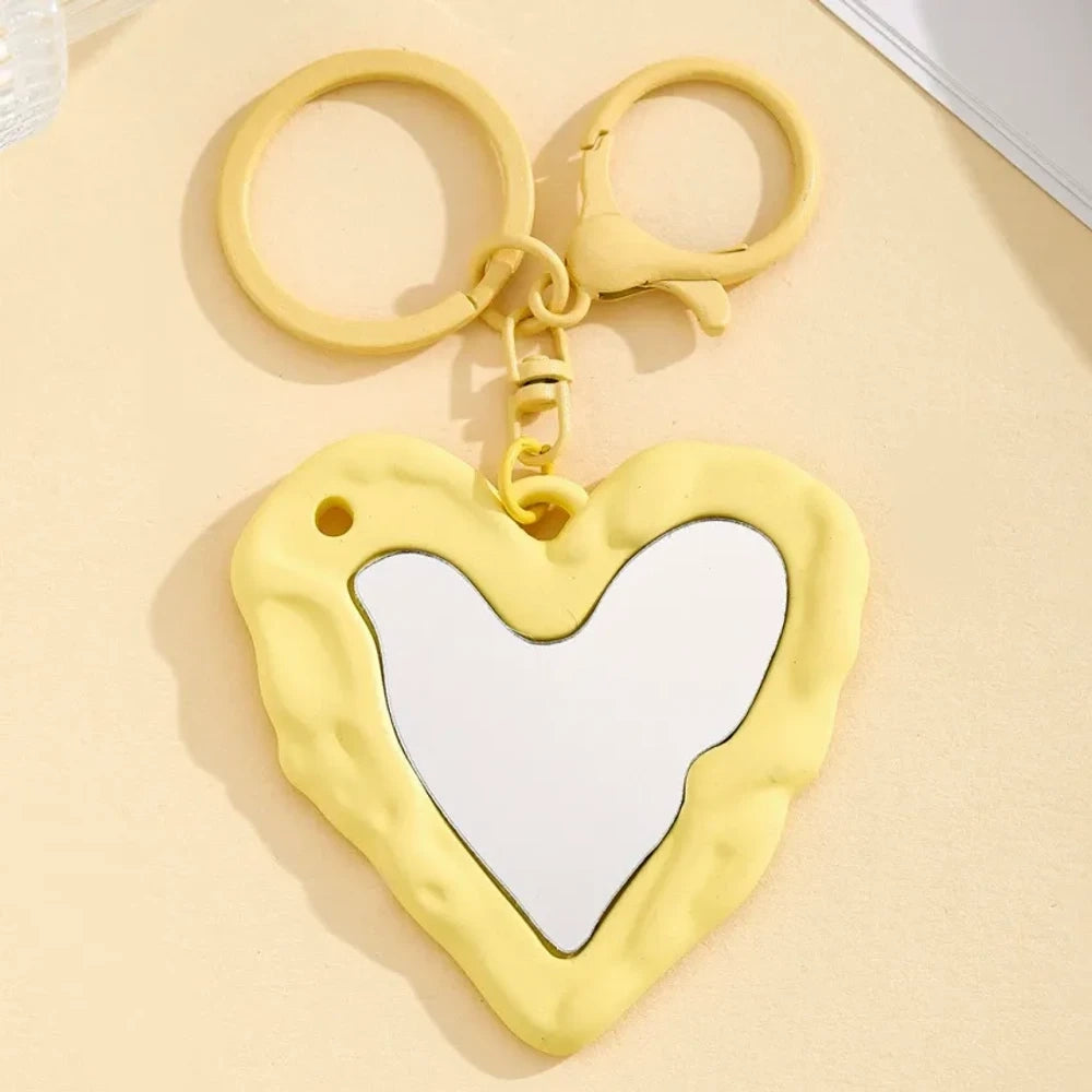 Nine colorful heart-shaped photo frame keychain pendants in purple, pink, hot pink, red, white, black, brown, yellow, and blue with lobster clasp rings on a beige surface. - 1