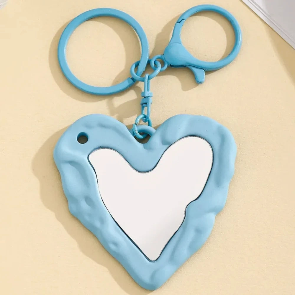 Nine colorful heart-shaped photo frame keychain pendants in purple, pink, hot pink, red, white, black, brown, yellow, and blue with lobster clasp rings on a beige surface. - 2