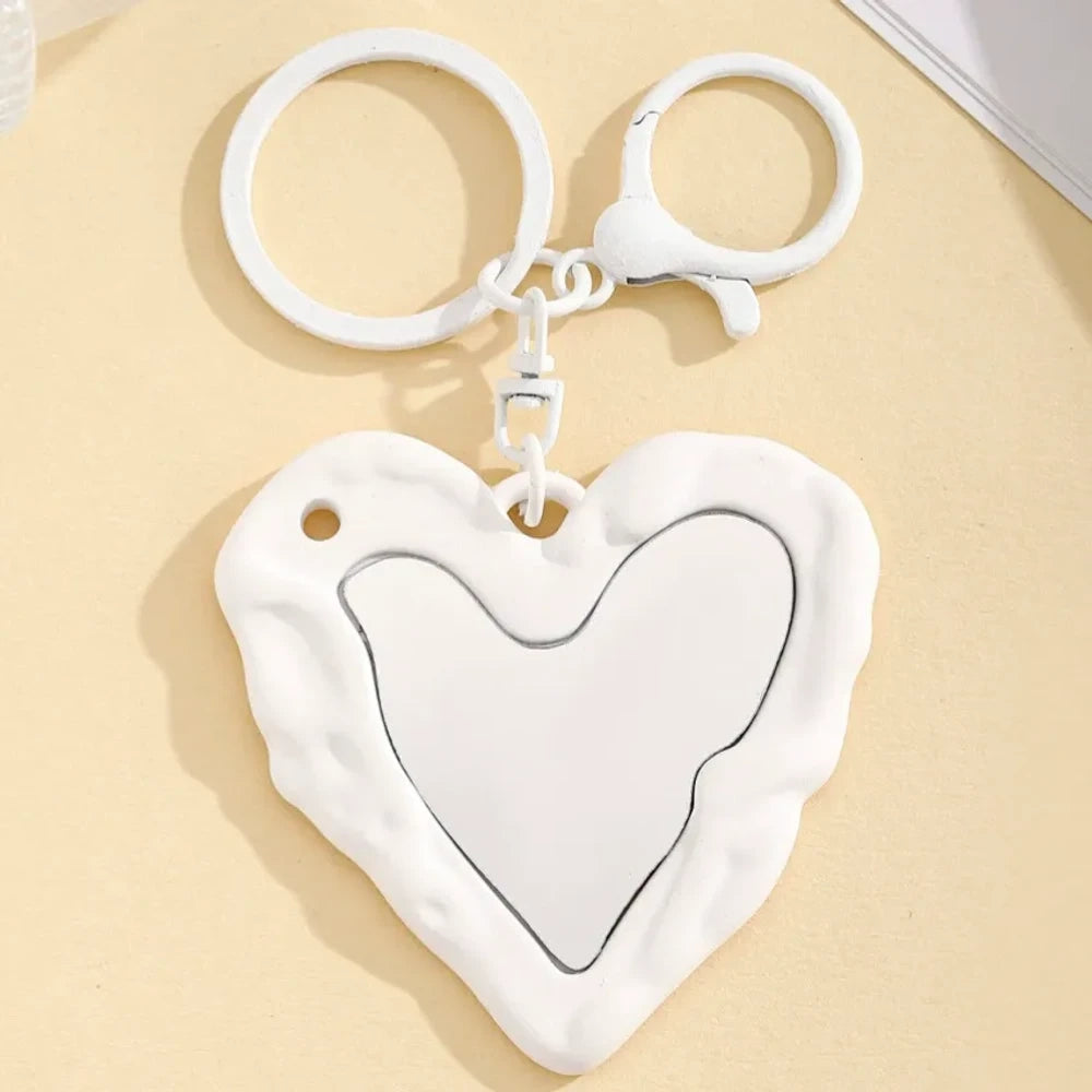 Nine colorful heart-shaped photo frame keychain pendants in purple, pink, hot pink, red, white, black, brown, yellow, and blue with lobster clasp rings on a beige surface. - 3