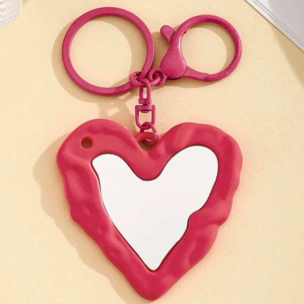 Nine colorful heart-shaped photo frame keychain pendants in purple, pink, hot pink, red, white, black, brown, yellow, and blue with lobster clasp rings on a beige surface. - 5