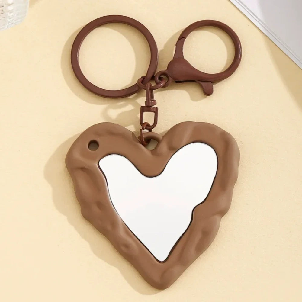 Nine colorful heart-shaped photo frame keychain pendants in purple, pink, hot pink, red, white, black, brown, yellow, and blue with lobster clasp rings on a beige surface. - 6