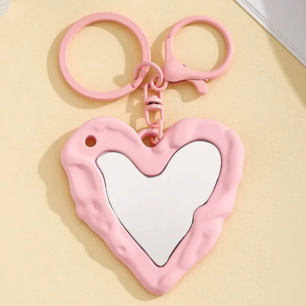 Nine colorful heart-shaped photo frame keychain pendants in purple, pink, hot pink, red, white, black, brown, yellow, and blue with lobster clasp rings on a beige surface. - 7