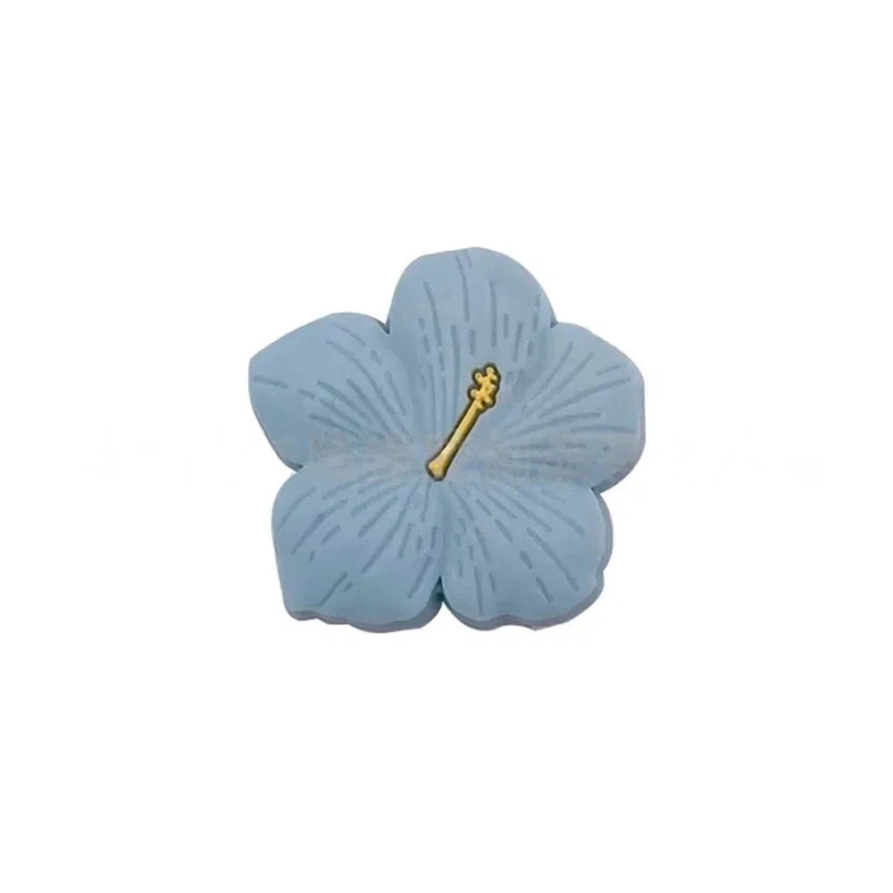 Assorted pastel and earthy tone hibiscus flower silicone focal beads with gold stamen detail displayed on a pink surface, available in colors including blue, purple, green, pink, mauve, brown, tan, yellow, and peach. - Royal Blue