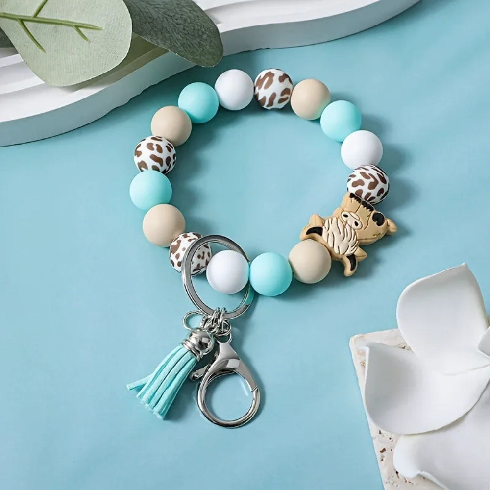 Highland cow silicone bead wristlet keychain bracelet with mint green, cream, white, and cow print beads, featuring a cute highland cow focal bead, lobster clasp, and teal and yellow tassels. - 1