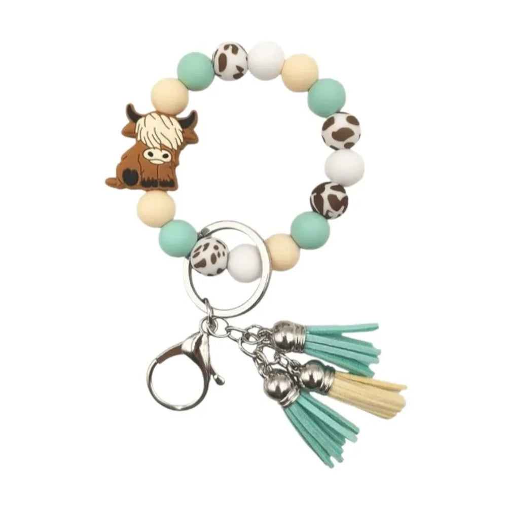 Highland cow silicone bead wristlet keychain bracelet with mint green, cream, white, and cow print beads, featuring a cute highland cow focal bead, lobster clasp, and teal and yellow tassels. - 2