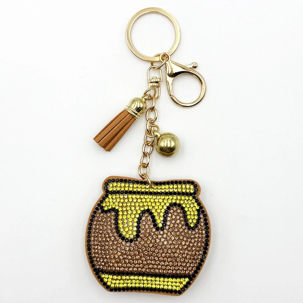 Rhinestone bling honey pot keychain charm with yellow and brown crystals, gold chain, tassel, and lobster clasp on white background.