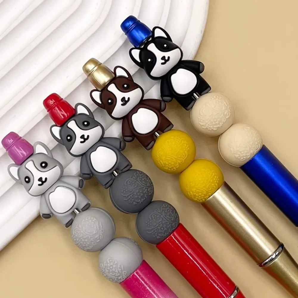 Four 3D husky dog silicone focal beads in gray, brown, black and white colorways displayed on decorative beadable pens with matching silicone round beads against a beige background.