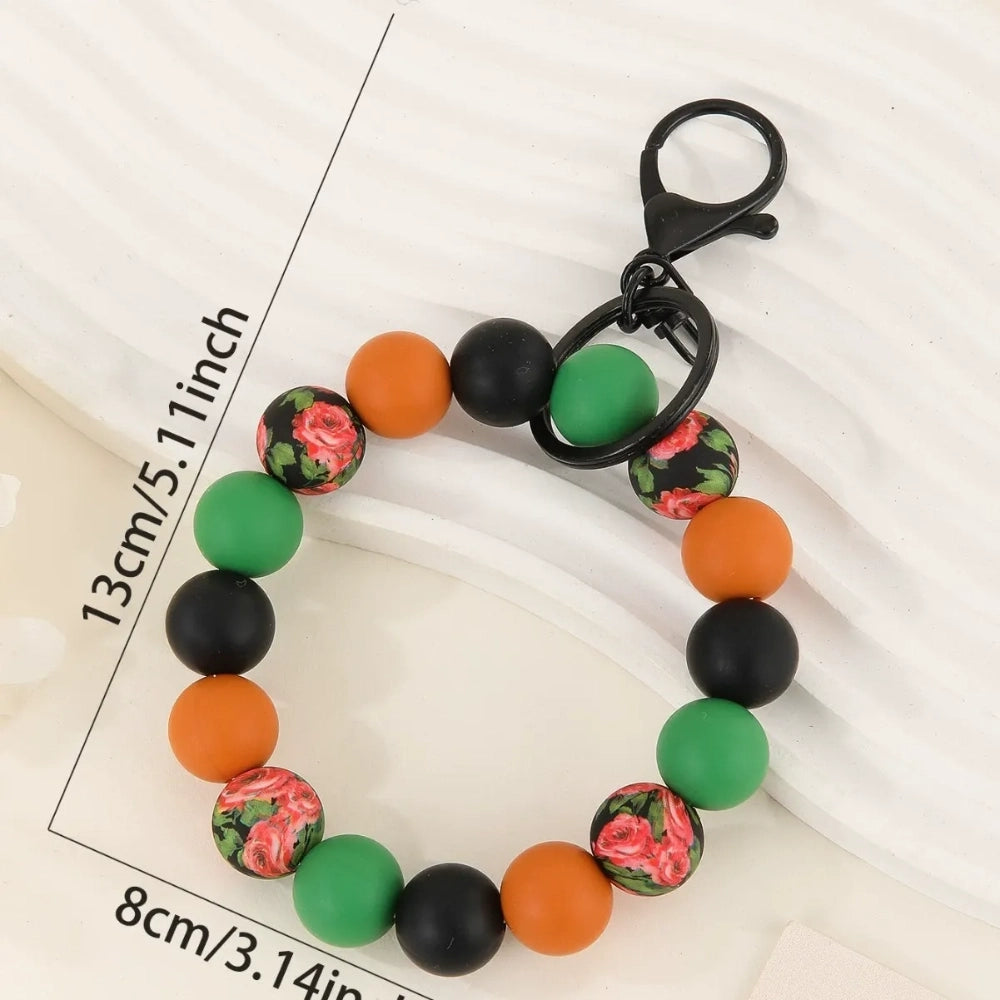 Four beaded silicone bead wristlet keychains featuring colorful jeep car printed silicone beads in red, teal, blue, and yellow with black and checkered beads and tassel accents. - Green