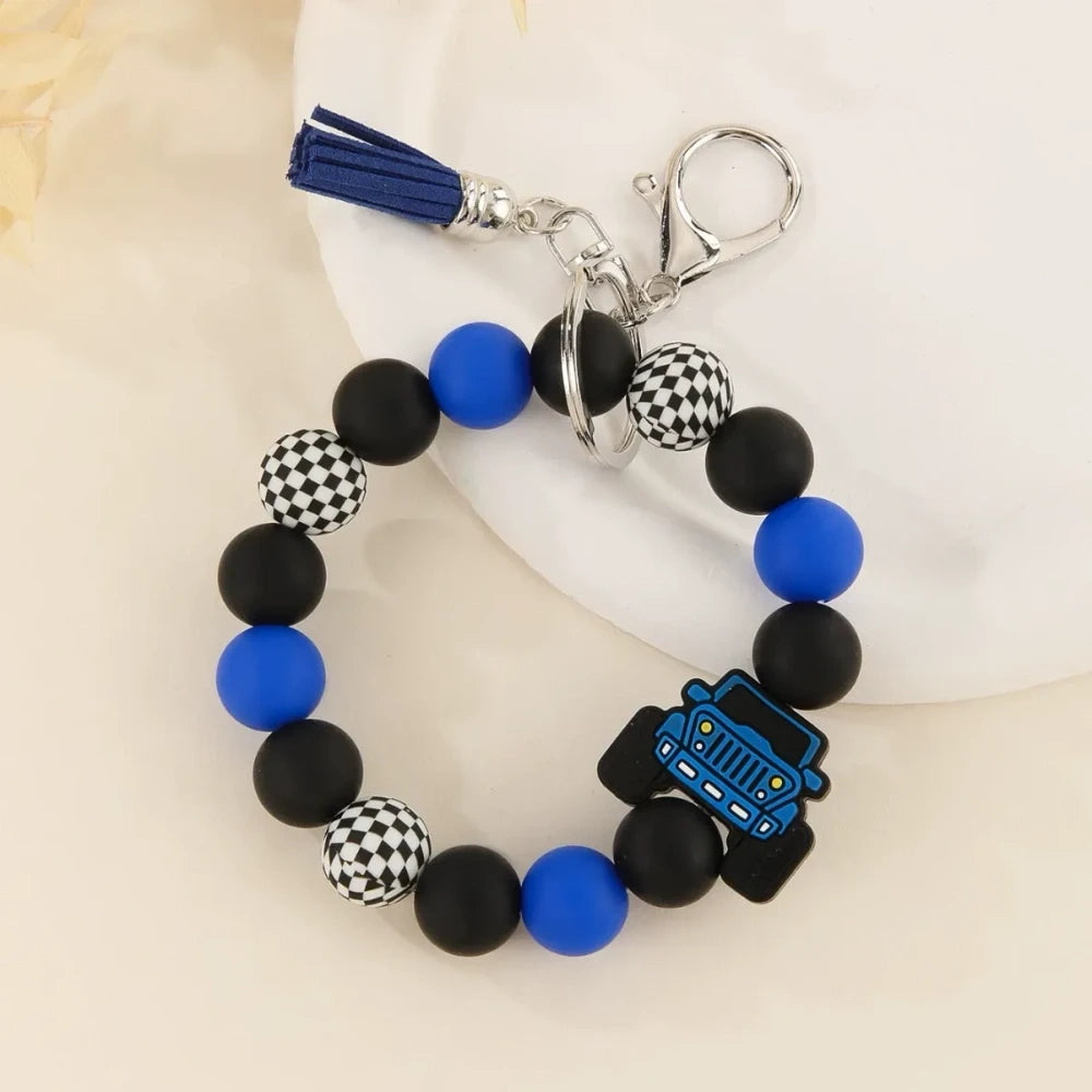 Four beaded bracelet keychains featuring jeep car silicone beads in red, teal, blue, and yellow with black and checkered beads and tassel accents on a white surface. - Blue
