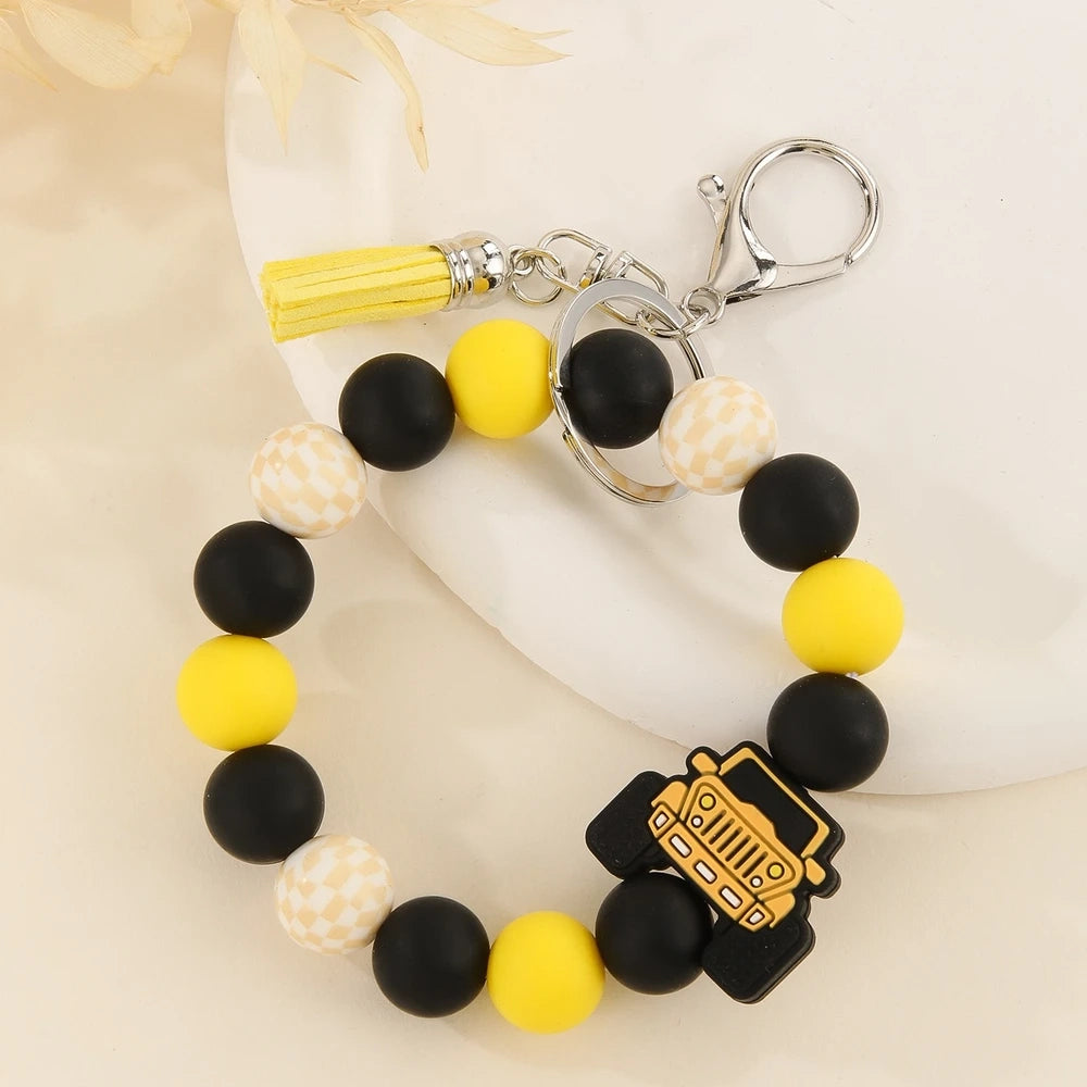 Four beaded bracelet keychains featuring jeep car silicone beads in red, teal, blue, and yellow with black and checkered beads and tassel accents on a white surface. - Yellow