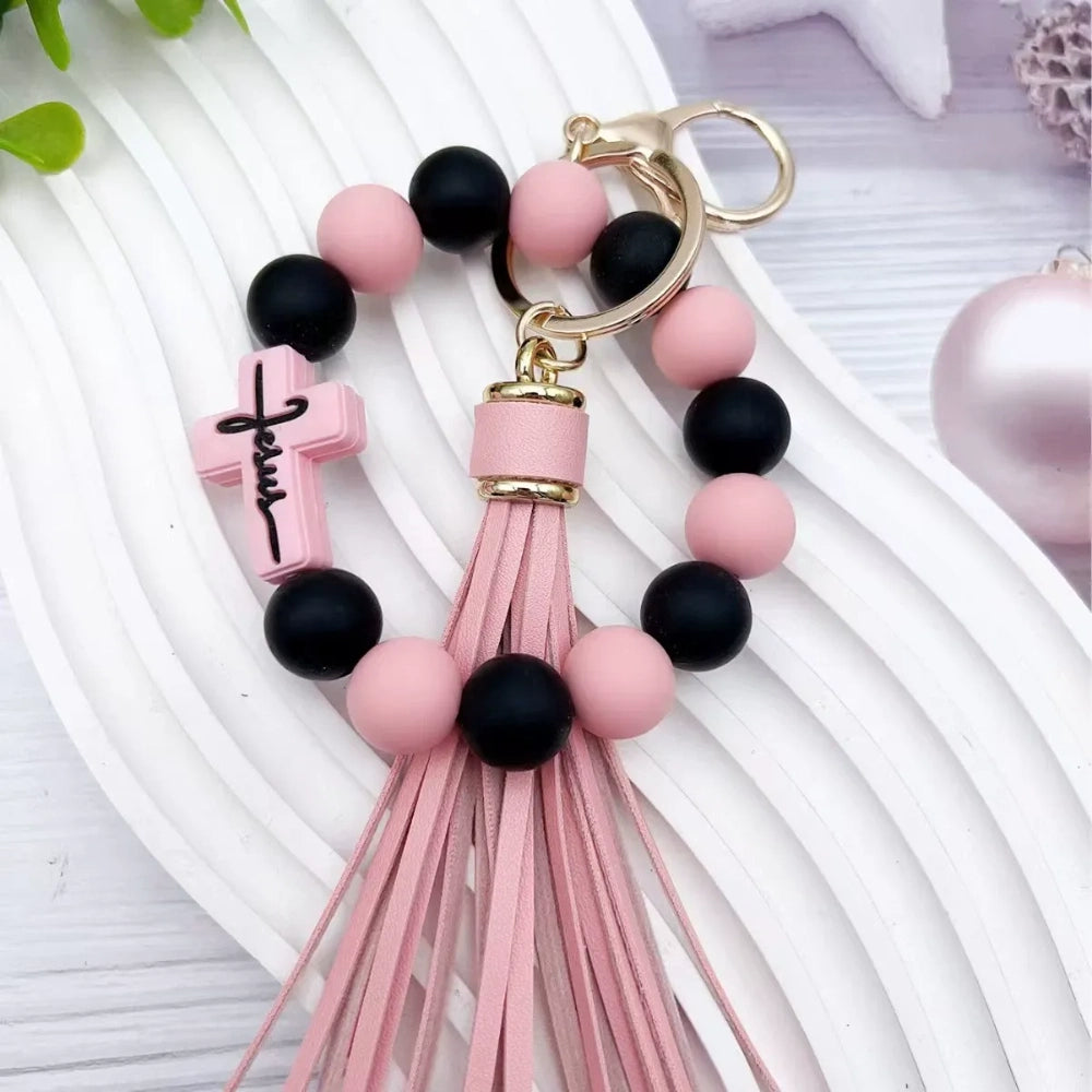 Colorful Jesus cross silicone bead stretch bracelets with tassel keychains in black, pink, purple, teal, and green color combinations on white background. - Pink-2