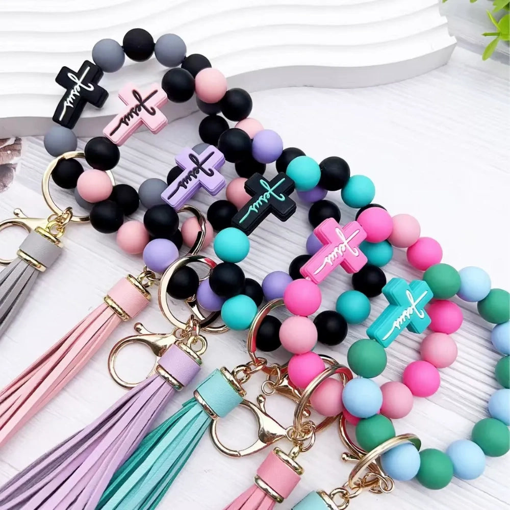 Colorful Jesus cross silicone bead stretch bracelets with tassel keychains in black, pink, purple, teal, and green color combinations on white background. - Random Mixed