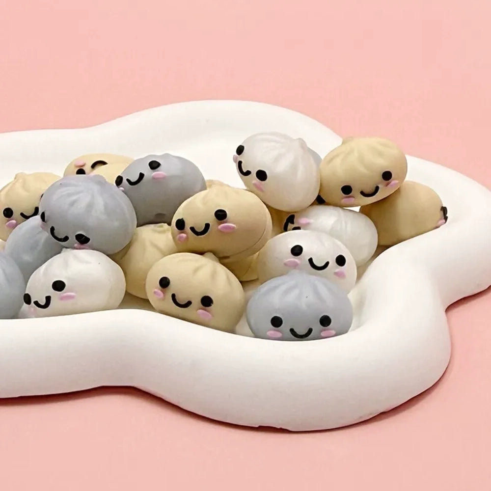 Cute kawaii smiley face dumpling bao bun silicone focal beads in cream, white, and gray colors piled in a cloud-shaped tray on a pink background - Random Mixed