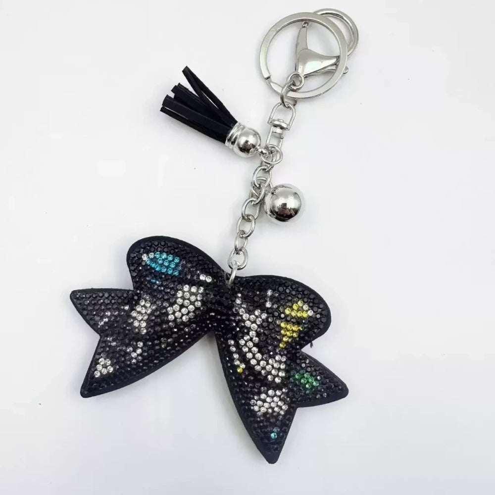 Large black bow-shaped fancy bead with AB rhinestone sparkle, shown styled as decorative keychain charms with tassels and silver hardware. - 2