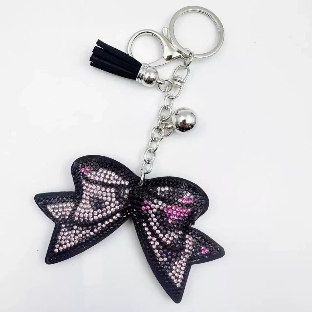 Large black bow-shaped fancy bead with AB rhinestone sparkle, shown styled as decorative keychain charms with tassels and silver hardware. - 3