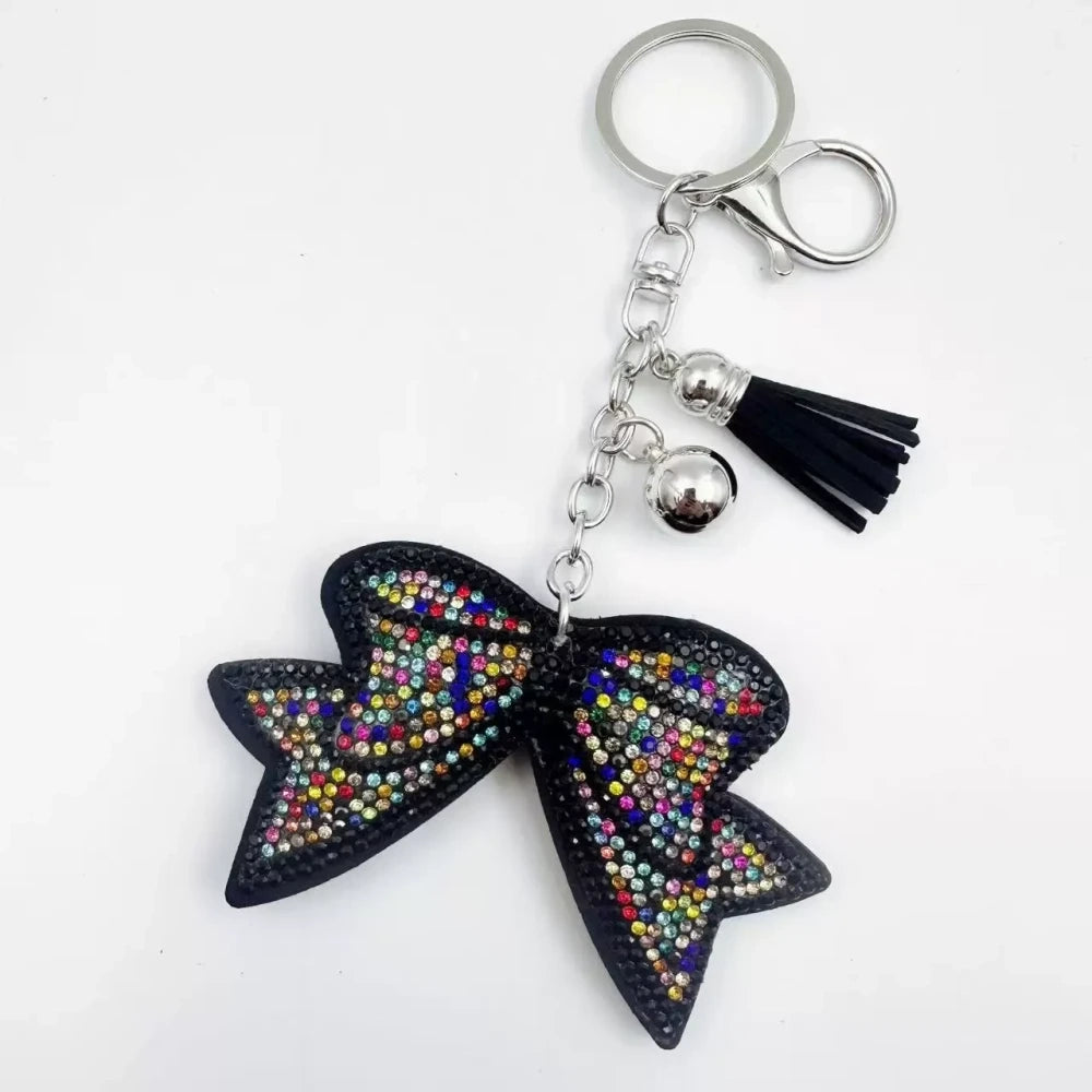 Large black bow-shaped fancy bead with AB rhinestone sparkle, shown styled as decorative keychain charms with tassels and silver hardware. - 4