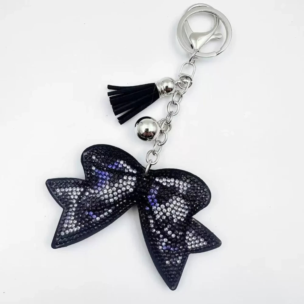 Large black bow-shaped fancy bead with AB rhinestone sparkle, shown styled as decorative keychain charms with tassels and silver hardware. - 5