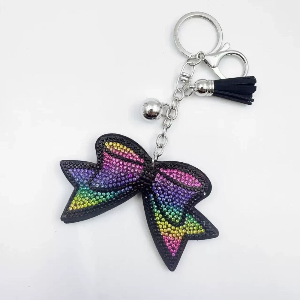 Large black bow-shaped fancy bead with AB rhinestone sparkle, shown styled as decorative keychain charms with tassels and silver hardware. - 7