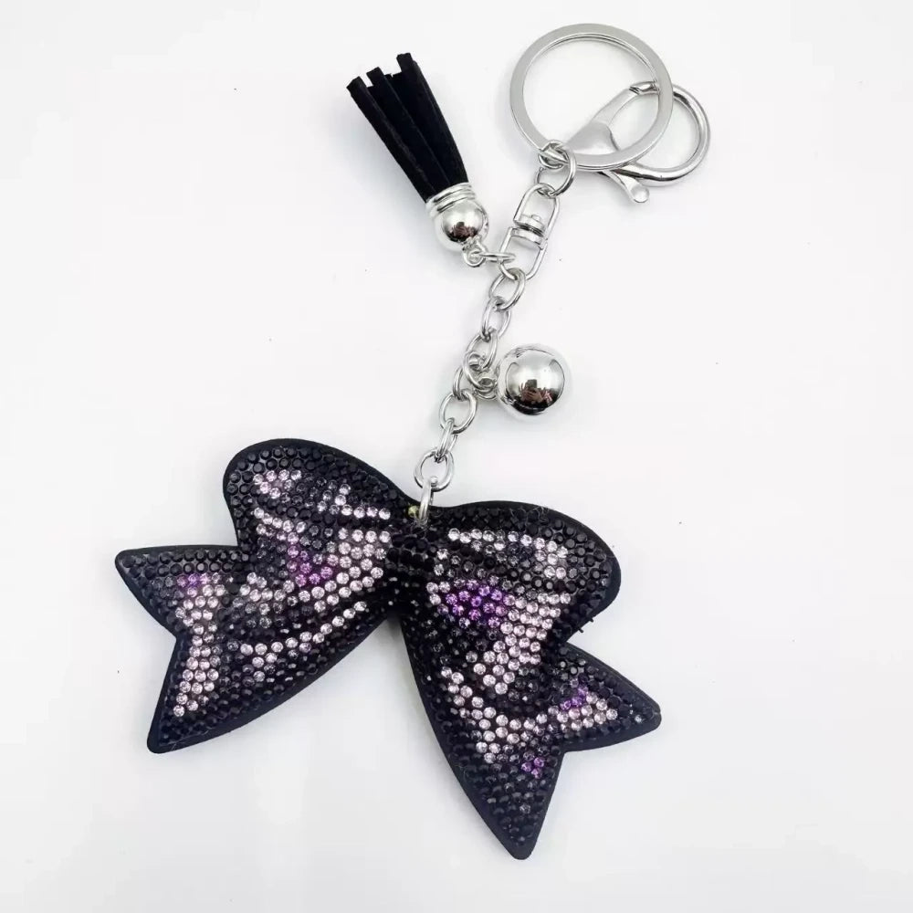 Large black bow-shaped fancy bead with AB rhinestone sparkle, shown styled as decorative keychain charms with tassels and silver hardware. - 8