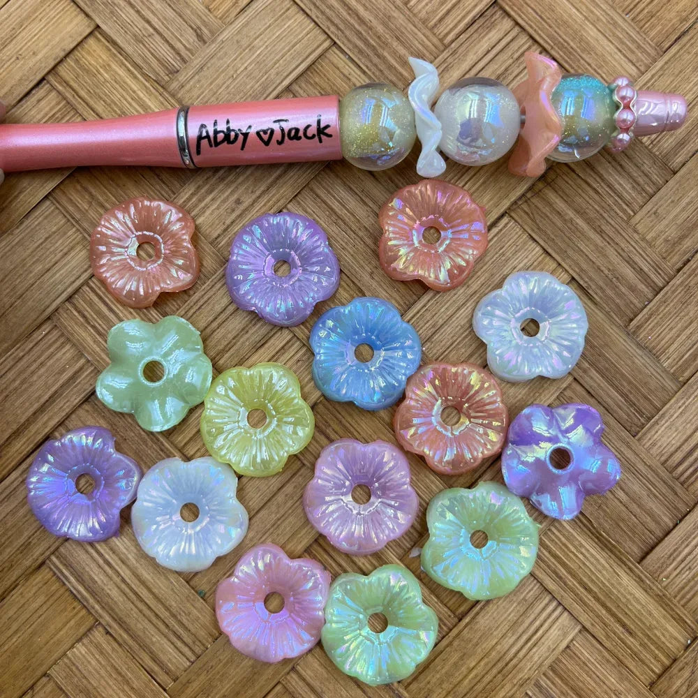Large pastel iridescent flower acrylic spacer beads shown with a pink beadable pen sample