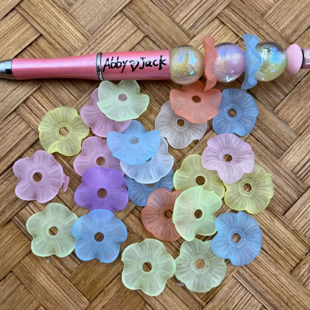 Pastel frosted flower acrylic spacer beads in assorted translucent colors shown with a beadable pen