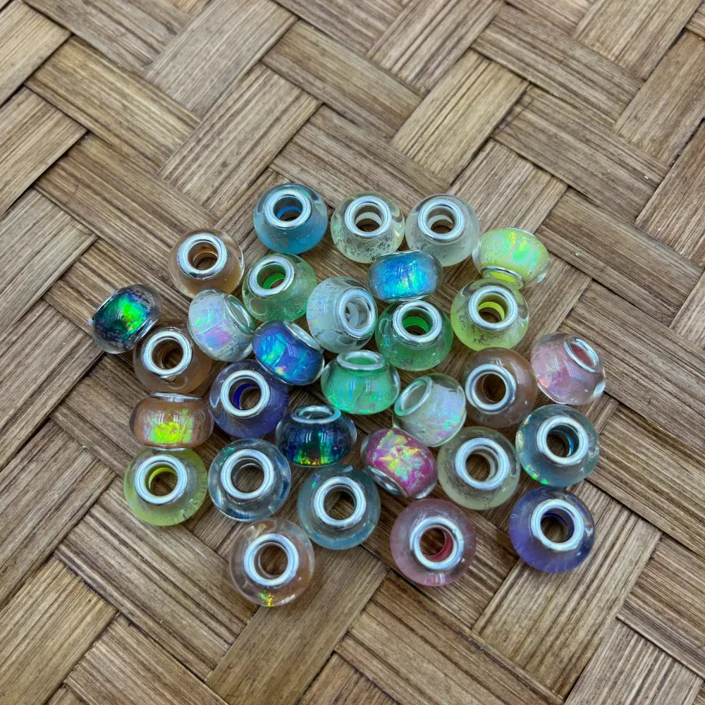 Mixed pastel iridescent acrylic spacer beads with large holes and opalescent crackle finish on a woven wood background