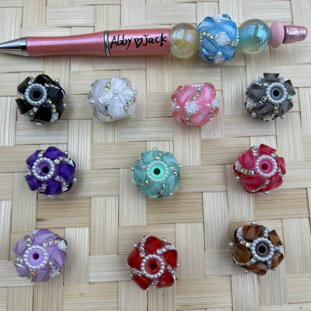 Assorted large hole swirl rhinestone acrylic fancy beads in multiple colors with a pink beadable pen example